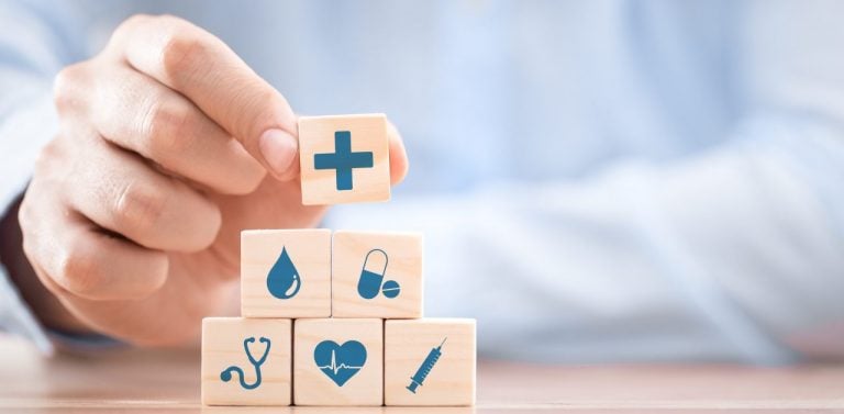 Hand holding building blocks with healthcare symbols