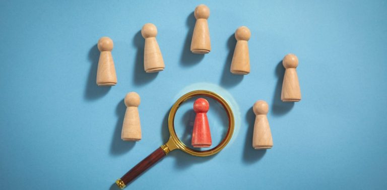 Wooden chess pieces with magnifying glass