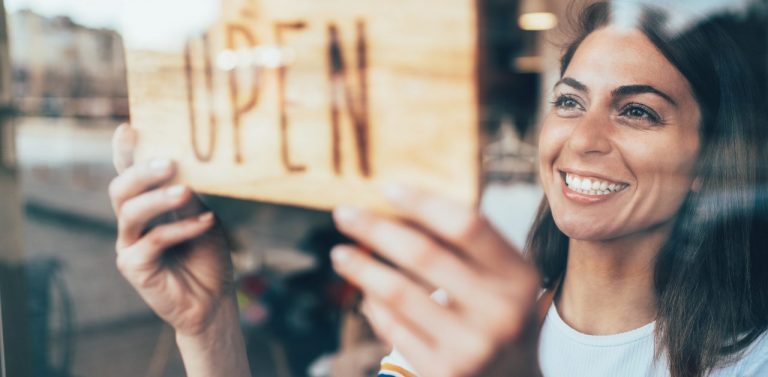 Woman small business owner putting up open sign