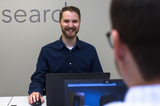 Business man at desk smiling and on laptop