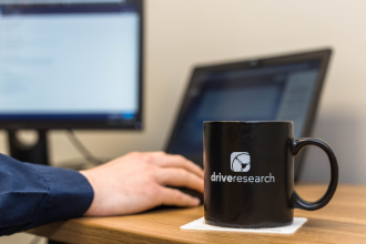 Person working at desk with Drive Research coffee mug