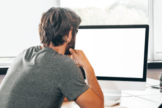 Bearded young businessman looking at computer at work