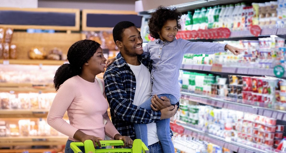 Family grocery shopping in dairy aisle looking at food options