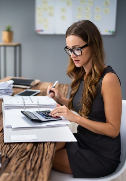 Female accountant using calculator at office desk