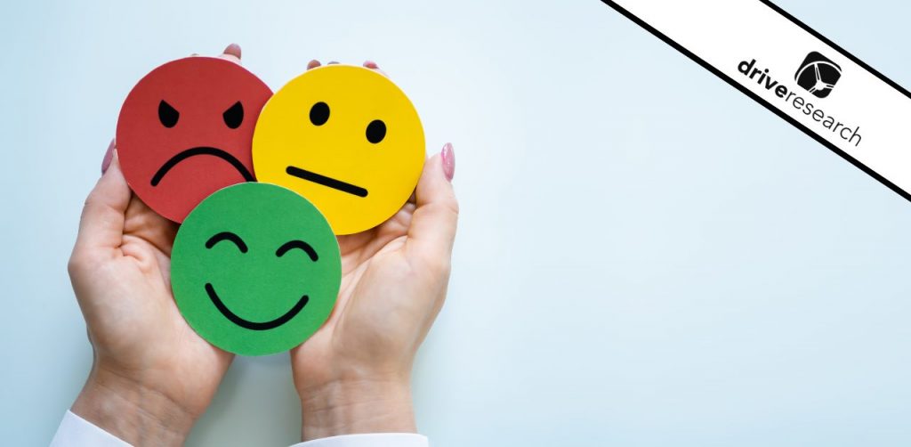 Hands holding circle paper cut outs of mad, neutral, and happy faces