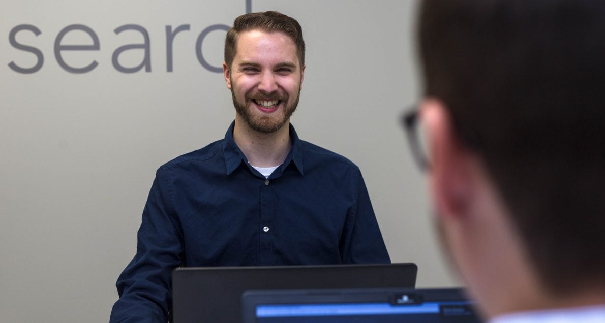 Male employee smiling at other unidentified coworker