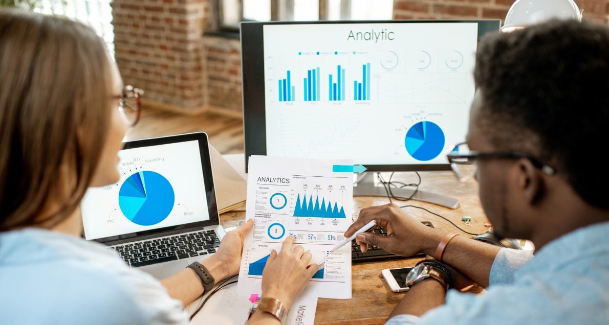 White female and african american male reviewing advanced data analysis charts