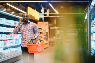 Young black male on phone while grocery shopping