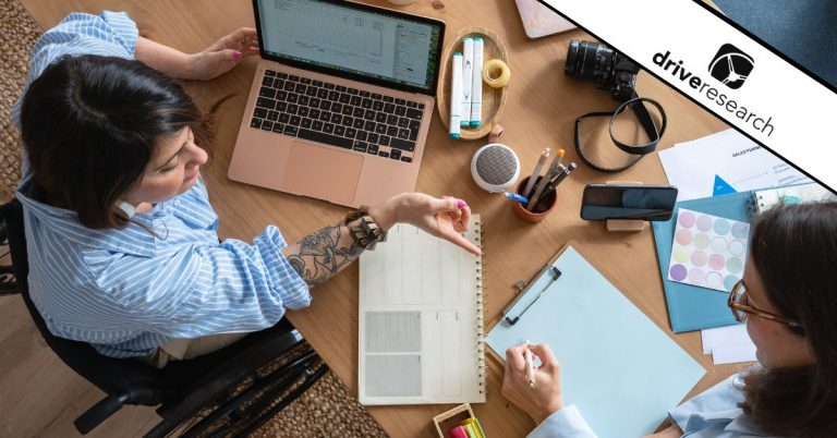 Two female employees collaborating at a desk - Drive Research