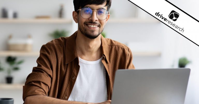 Male with glasses smiling on his laptop with coffee