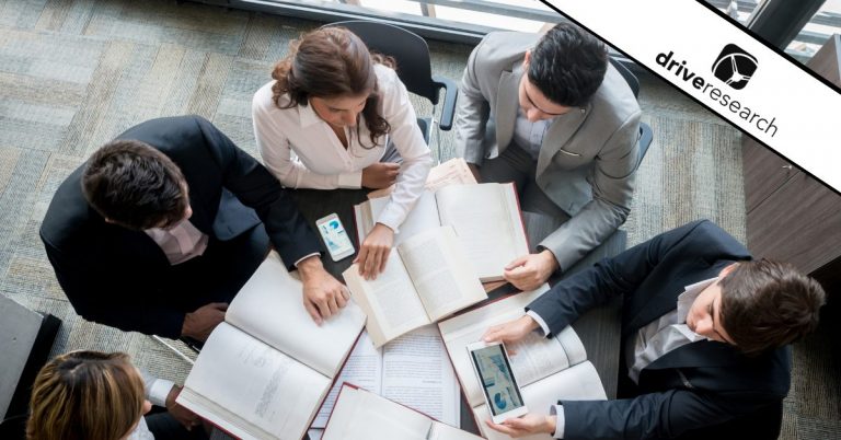 People around a desk looking at charts and books