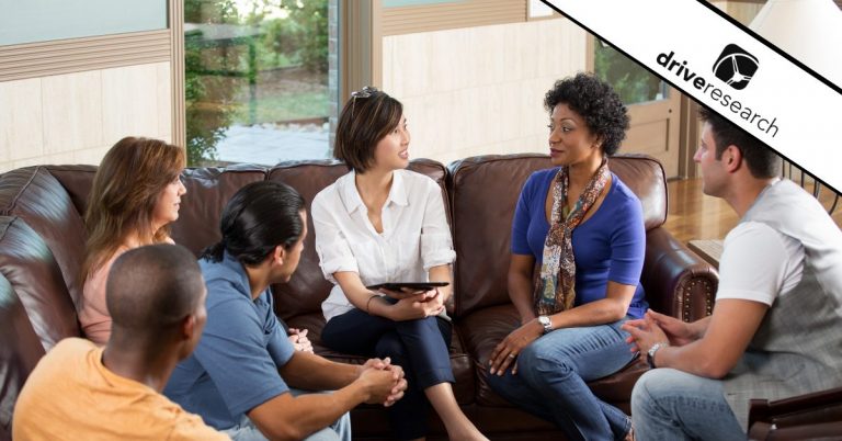 a group of people meeting in the living room with one holding a tablet showing a food and beverage focus group