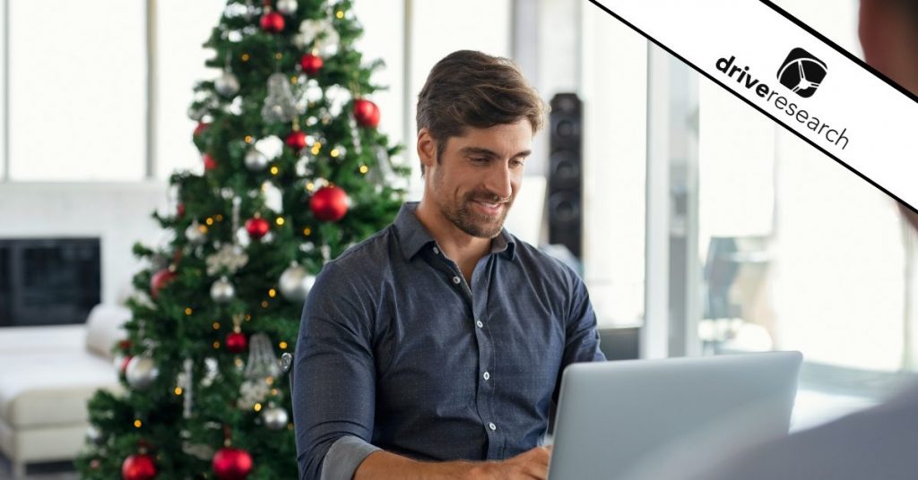 a man on his computer with a christmas tree behind him filling out a holiday survey