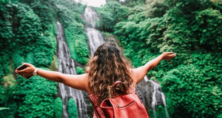 Anonymous female traveler admiring amazing waterfall