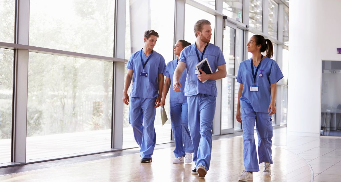 Healthcare workers in scrubs walking in hallway