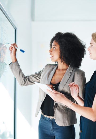 Two women developing a brand new plan on whiteboard