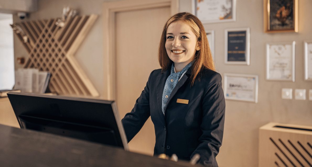 Female Worker At Hotel Reception Desk