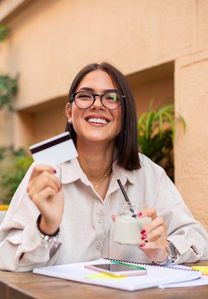 Female with glasses smiling with credit card in hand