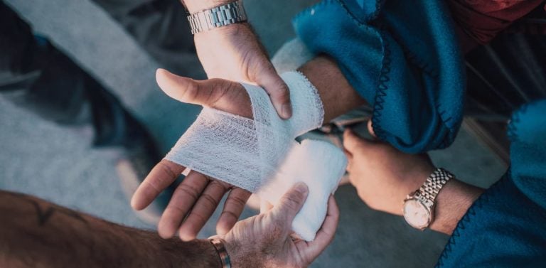 Person Applying Bandage on Another Person's Hand