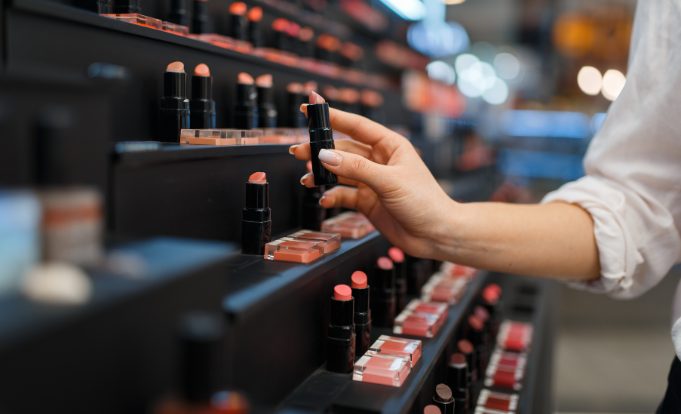 Woman Takes Lipstick from Shelf in Cosmetics Store