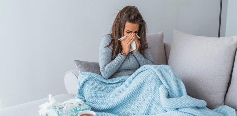 Woman on couch using tissues and cold products