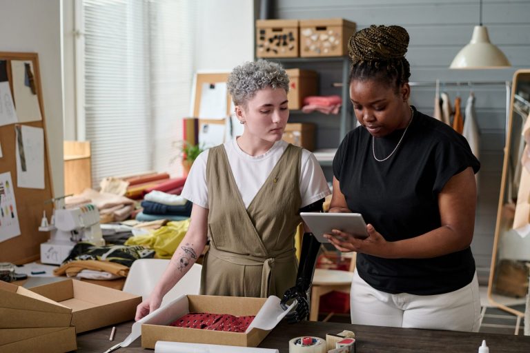 Two young intercultural females checking address of client while packing order