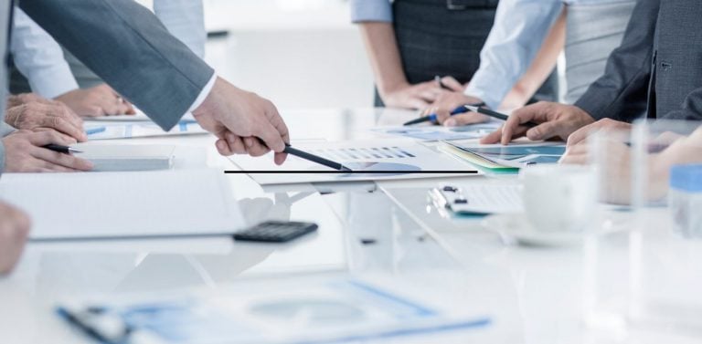 Employees gathered around table reviewing charts and stats