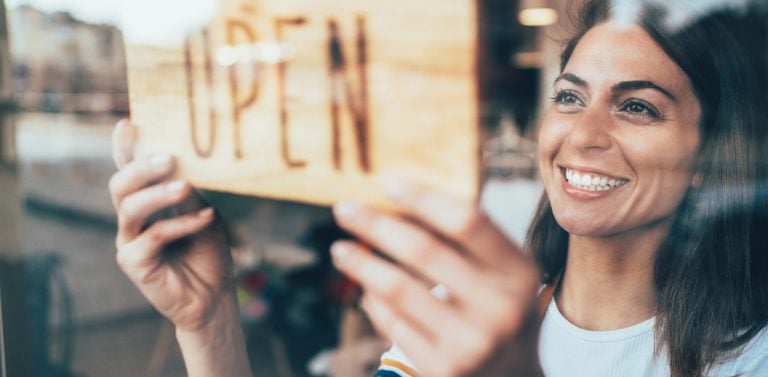 Female business owner hanging open sign