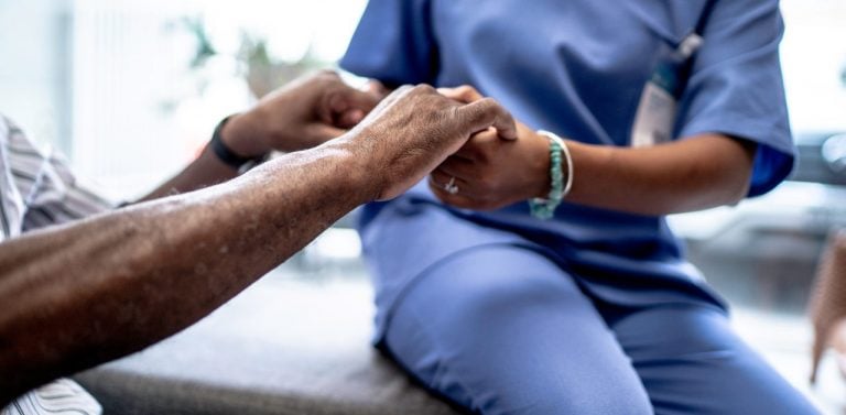 Patient and medical professional holding hands