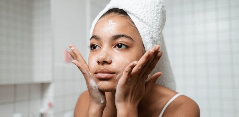 Woman in White Tank Top Washing Her Face With Soap