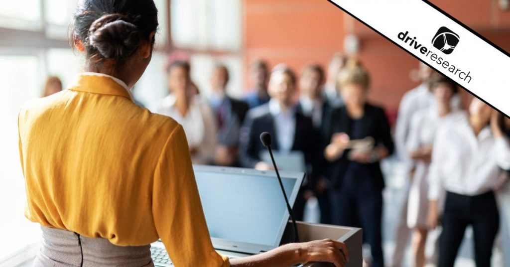 Woman speak at podium to crowd