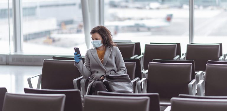 Women in airport sitting and wearing a mask